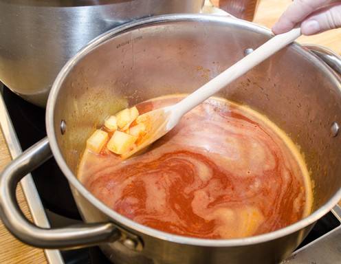 Mit Suppe ablöschen und die Eräpfel sowie die Gewürze hinzugeben.