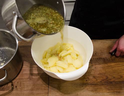 Die Suppe zu den in Scheiben geschnittenen Erdäpfeln hinzugeben.