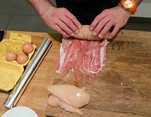 Setzen Sie die Hühnerbrust auf ein Ende des Prosciutto