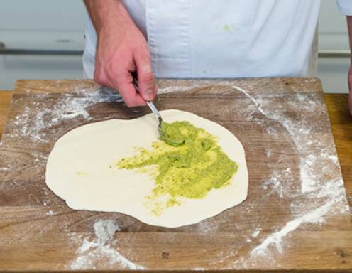 Bestreichen Sie den Teig mit Rucola